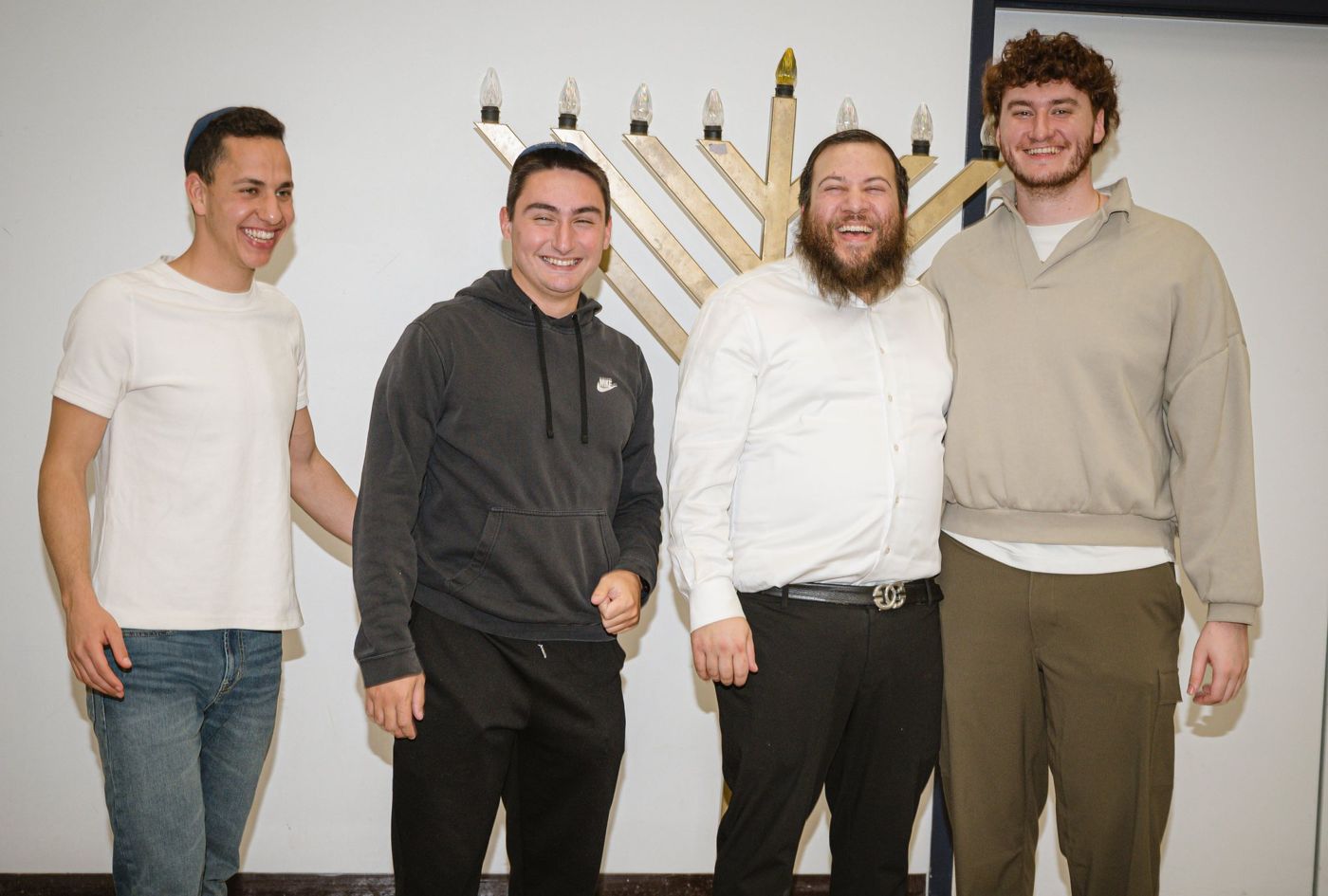Rabbi Greenberg laughing with students beside a menorah